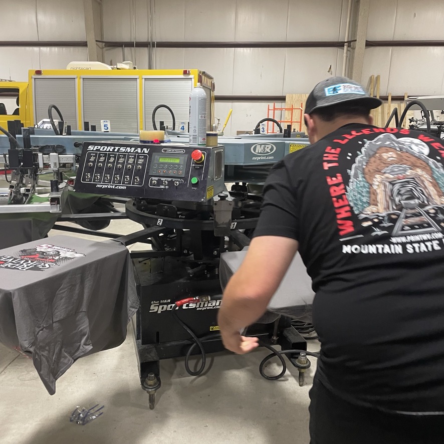 Screen printer working at a press with a printed black T-shirt