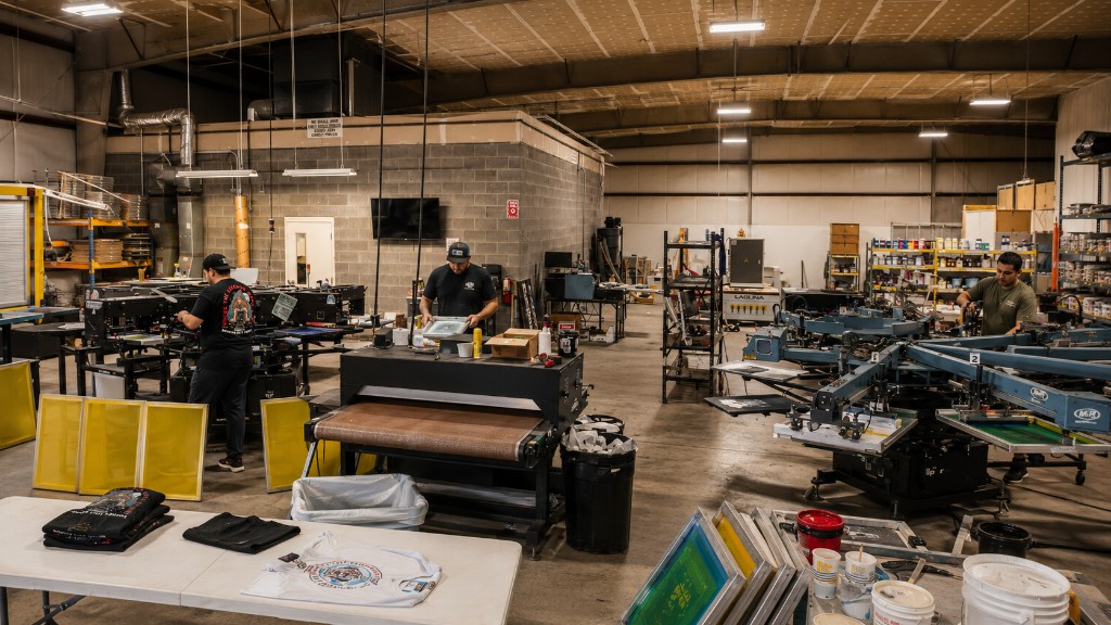 Screen printers working on presses and a conveyor dryer in a shop