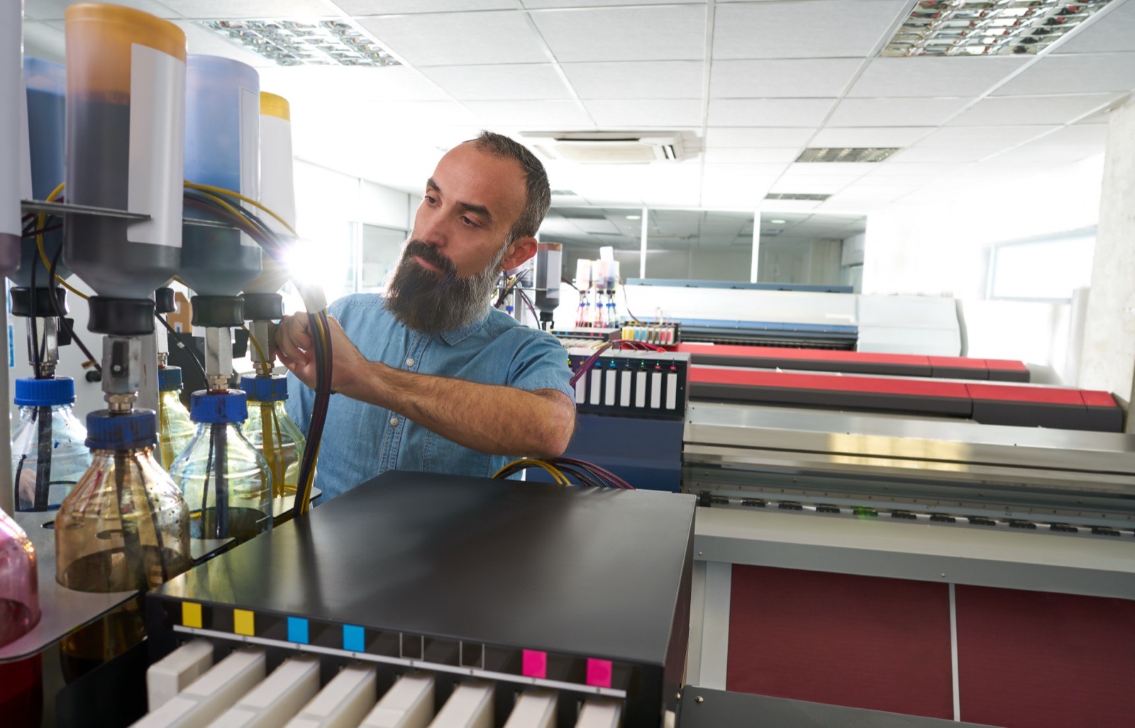 Print shop worker preparing a wide-format printer used for sign graphics